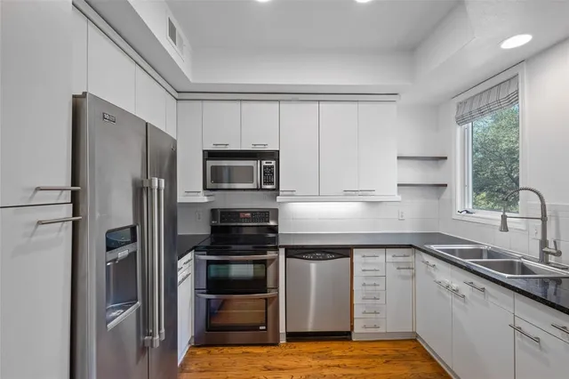 a kitchen with white cabinets stainless steel appliances and window