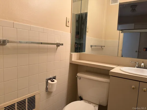 a bathroom with a granite countertop toilet sink and mirror