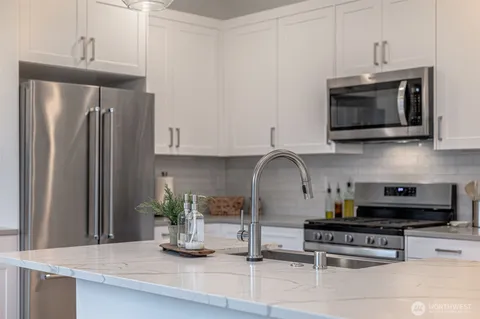 a kitchen with stainless steel appliances a sink a stove and cabinets