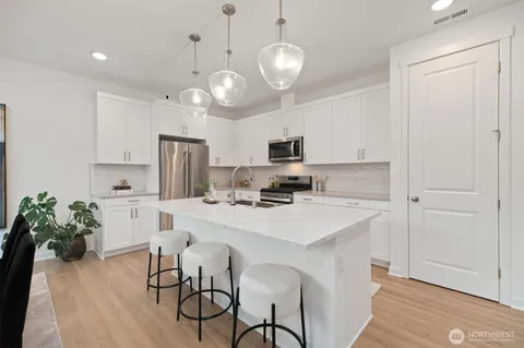 a kitchen with a refrigerator a stove cabinets dining table and chairs