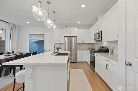 a large kitchen with kitchen island a stove a sink a dining table and chairs