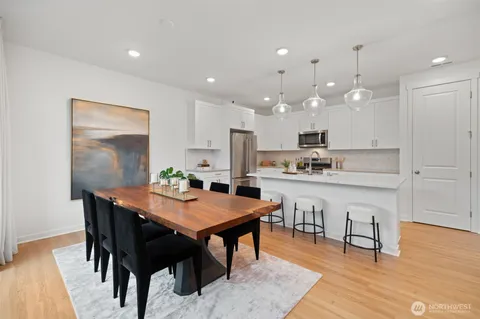 a kitchen with a dining table chairs and wooden floor