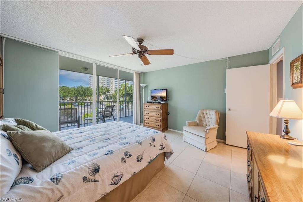 3 Bluebill Avenue, Unit 207 Naples, FL 34108 - Photo 18 of 32 a bedroom with a bed a chair and a large window