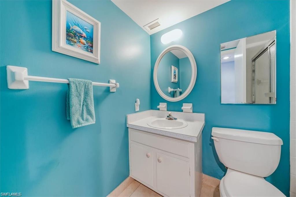 3 Bluebill Avenue, Unit 207 Naples, FL 34108 - Photo 21 of 32 a bathroom with a toilet a sink and mirror