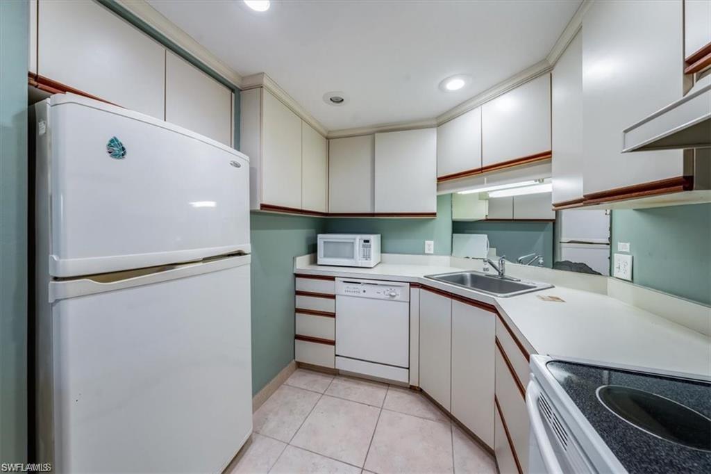 3 Bluebill Avenue, Unit 207 Naples, FL 34108 - Photo 28 of 32 a kitchen with a sink a refrigerator and cabinets
