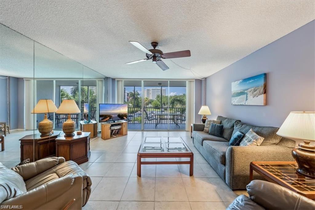 3 Bluebill Avenue, Unit 207 Naples, FL 34108 - Photo 10 of 32 a living room with furniture a chandelier and a large window