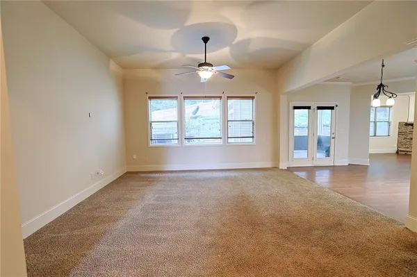 an empty room with chandelier fan and windows