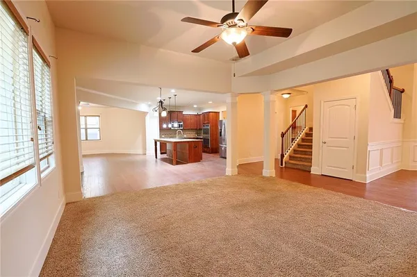 an empty room with chandelier fan and windows
