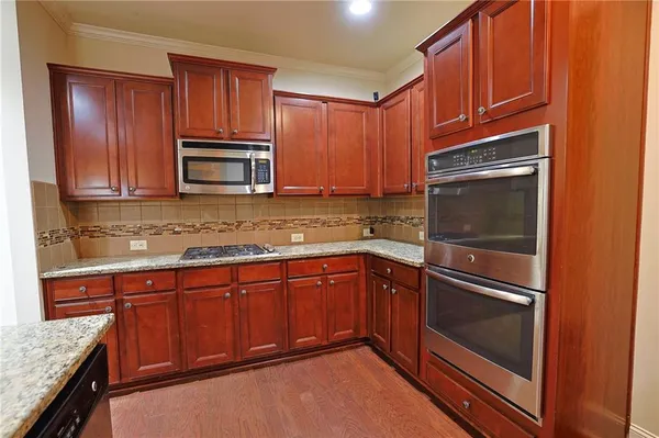 a kitchen with stainless steel appliances granite countertop a refrigerator a stove top oven a sink dishwasher and a refrigerator with wooden floor