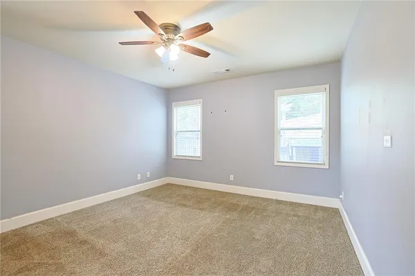 an empty room with fan and windows