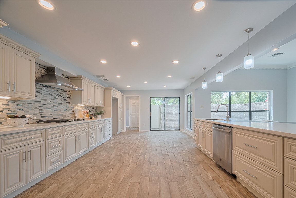 15600 Barkers Landing Road, Unit 20 Houston, TX 77079 - Photo 10 of 49 This kitchen features modern cabinetry with ample storage, a stylish tiled backsplash, and stainless steel appliances. The open layout includes recessed lighting and pendant lights, enhancing the spacious feel. Large windows and sliding doors provide plenty of natural light, leading to an outdoor area.