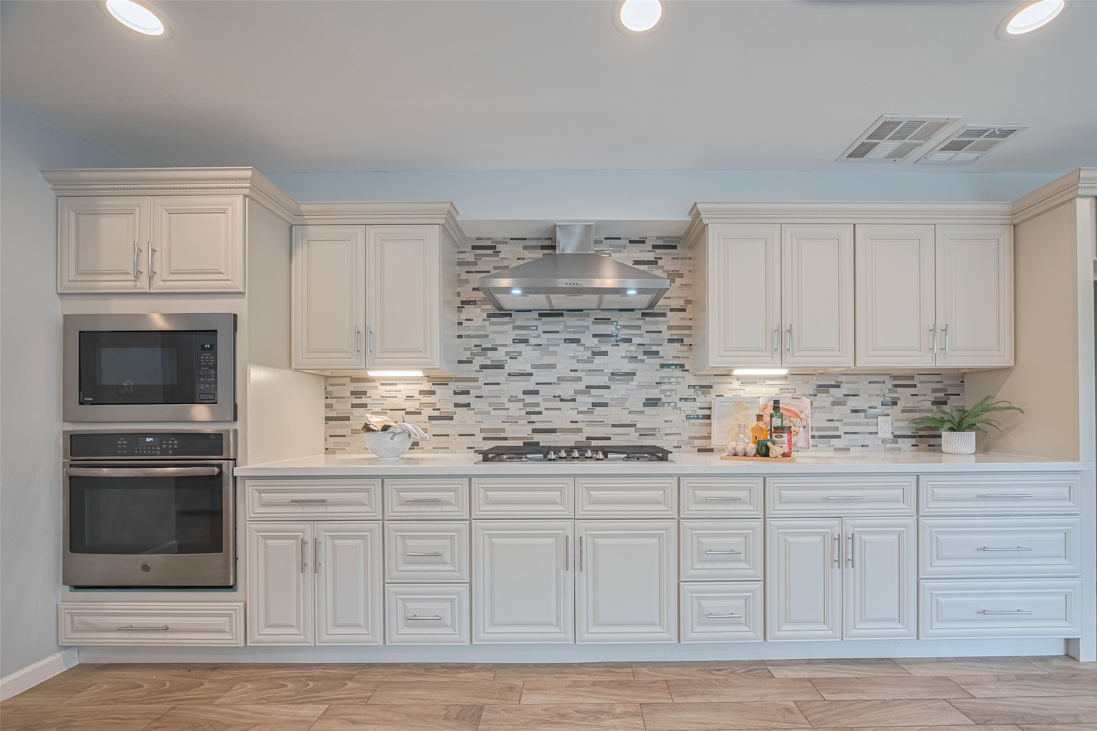 15600 Barkers Landing Road, Unit 20 Houston, TX 77079 - Photo 13 of 49 This kitchen features elegant white cabinetry with ample storage, stainless steel appliances, and a modern backsplash. A sleek range hood complements the design, while under-cabinet lighting enhances the workspace. SS appliances include a gas cooktop, microwave and convection oven.