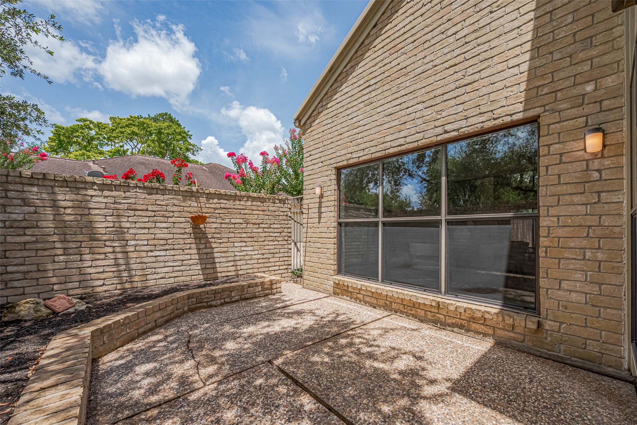 15600 Barkers Landing Road, Unit 20 Houston, TX 77079 - Photo 23 of 49 This photo showcases a charming outdoor patio area with brick walls offering a private and inviting space for relaxation or entertaining. Big enough for a BBQ to grill some hamburgers or steaks for family or friends under the canopy of the tree.