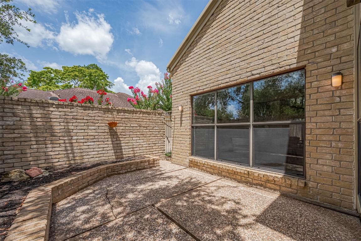 15600 Barkers Landing Road, Unit 20 Houston, TX 77079 - Photo 23 of 49 This photo showcases a charming outdoor patio area with brick walls offering a private and inviting space for relaxation or entertaining. Big enough for a BBQ to grill some hamburgers or steaks for family or friends under the canopy of the tree.
