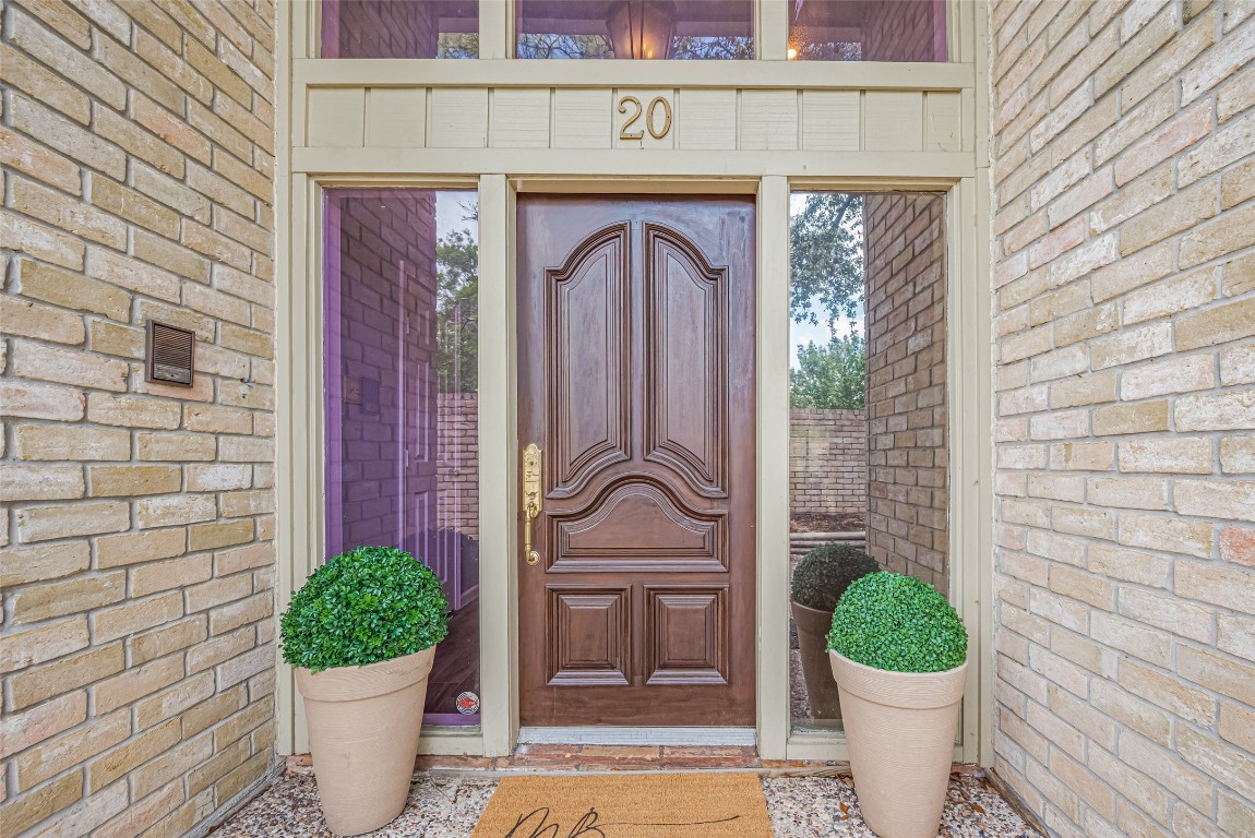 15600 Barkers Landing Road, Unit 20 Houston, TX 77079 - Photo 2 of 49 This photo showcases a welcoming front entrance with a beautifully crafted wooden door, flanked by tall side windows. The brick exterior enhances the classic look.