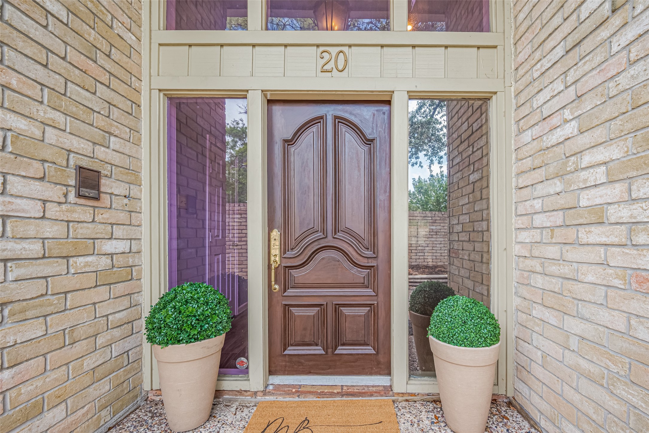 15600 Barkers Landing Road, Unit 20 Houston, TX 77079 - Photo 2 of 49 This photo showcases a welcoming front entrance with a beautifully crafted wooden door, flanked by tall side windows. The brick exterior enhances the classic look.
