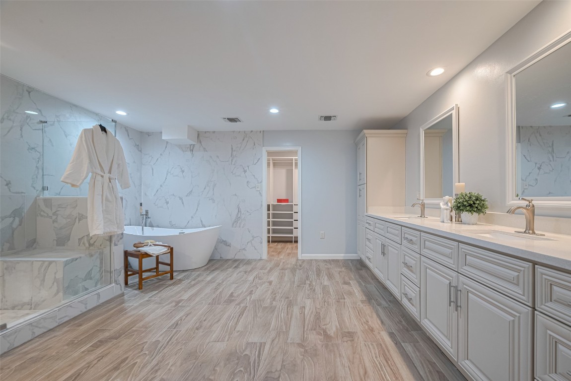 15600 Barkers Landing Road, Unit 20 Houston, TX 77079 - Photo 30 of 49 Luxurious and modern Primary bathroom featuring a sleek freestanding tub, large glass-enclosed shower, dual vanity with ample storage. A walk-in closet is accessible directly from the bathroom, enhancing convenience and luxury.