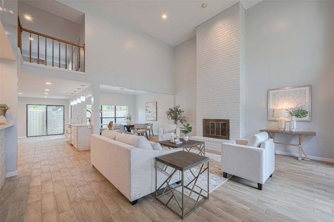 15600 Barkers Landing Road, Unit 20 Houston, TX 77079 - Photo 5 of 49 This spacious living area features high ceilings, a modern open layout, and abundant natural light. The elegant room includes a tall white brick fireplace, and a view into the open kitchen and dining space, creating an inviting and cohesive environment.
