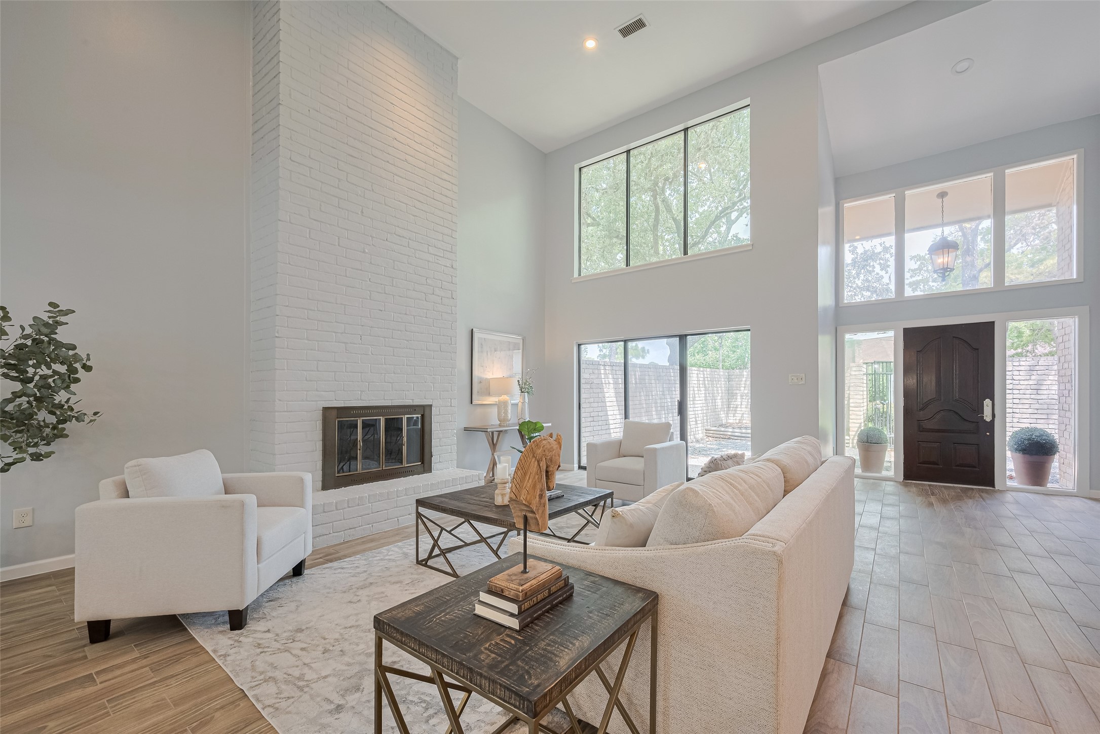 15600 Barkers Landing Road, Unit 20 Houston, TX 77079 - Photo 6 of 49 Another view of the living room features high ceilings, a large brick fireplace, and abundant natural light from multiple windows. Wood like flooring in all first floor.