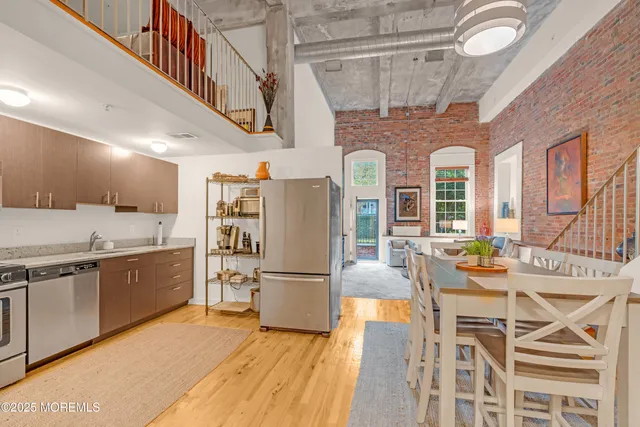 a kitchen with stainless steel appliances granite countertop a refrigerator a stove and a dining table with wooden floor