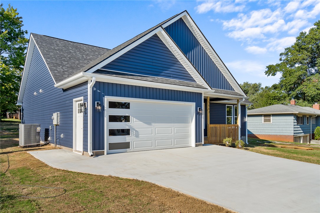 1507 Tindall Avenue Anderson, SC 29621 - Photo 2 of 38 Bold blue siding pairs with a sleek concrete driveway and a modern garage door.