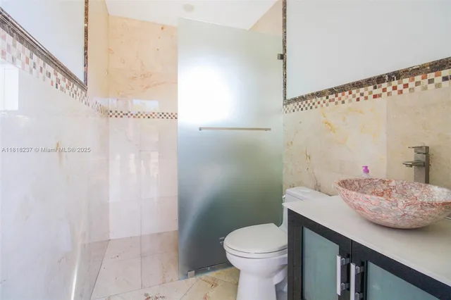 a bathroom with a granite countertop sink a toilet and shower