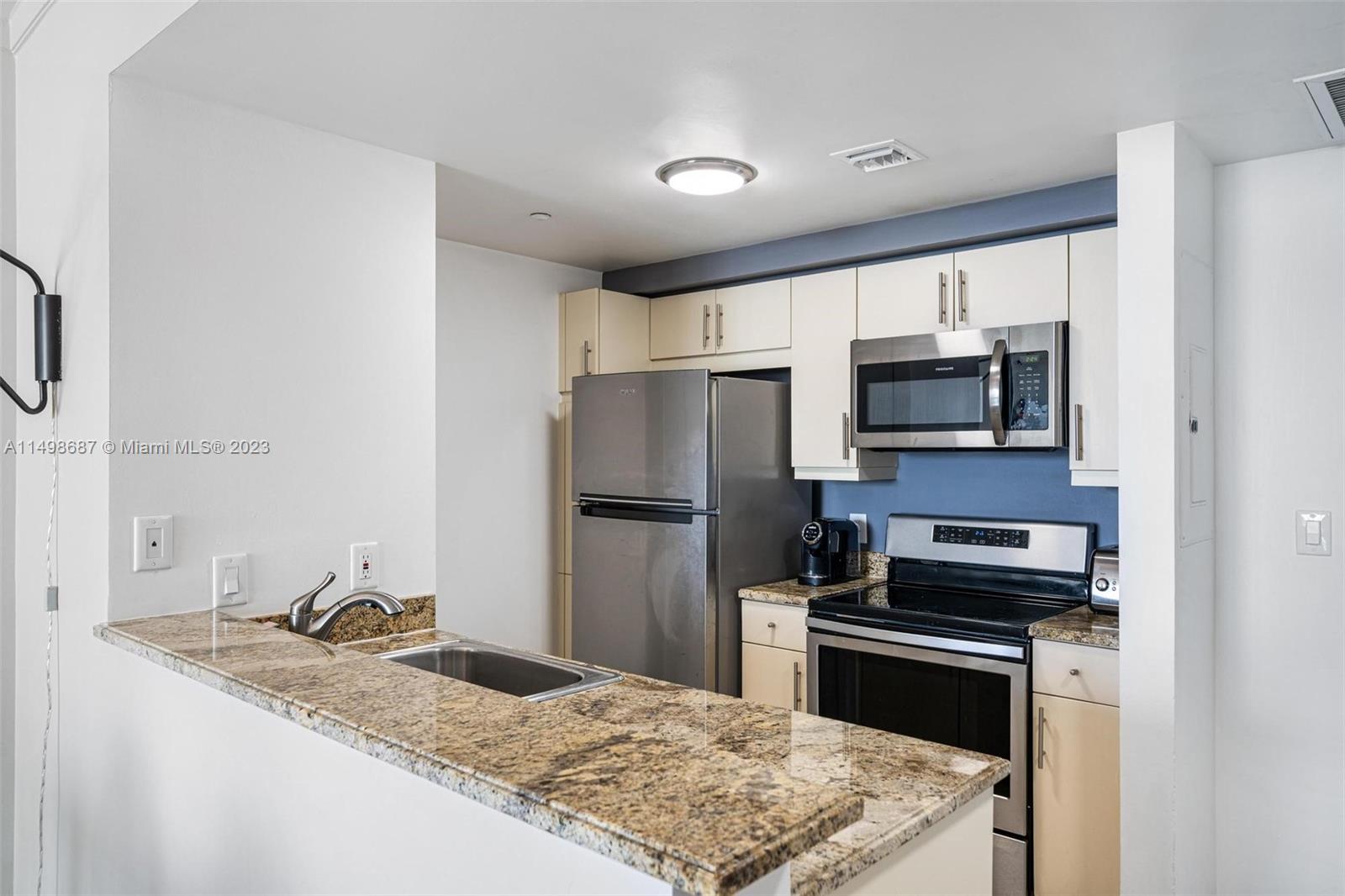 2889 McFarlane Road, Unit 1414 Miami, FL 33133 - Photo 5 of 15 a kitchen with a sink stove and refrigerator