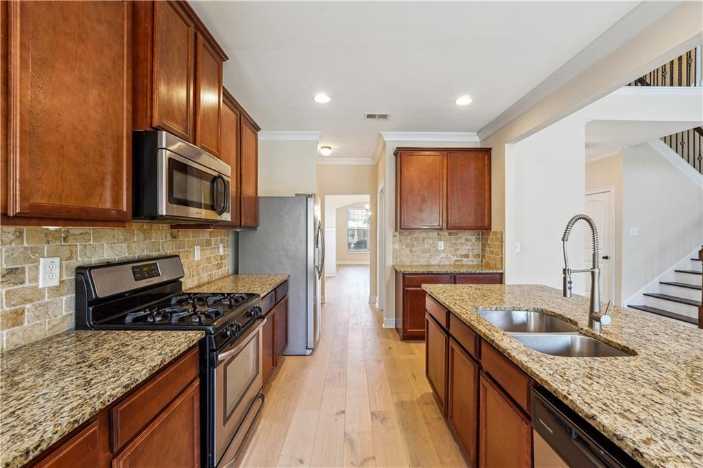 5145 Rialto Way Cumming, GA 30040 - Photo 7 of 25 a kitchen with stainless steel appliances granite countertop a sink stove microwave and refrigerator