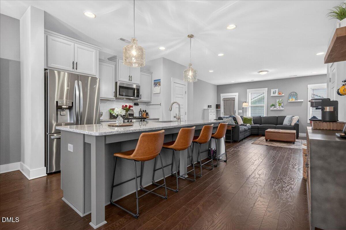 251 Daniel Ridge Road Wendell, NC 27591 - Photo 13 of 73 a large kitchen with stainless steel appliances kitchen island granite countertop a large refrigerator a sink dishwasher a dining table and chairs with wooden floor