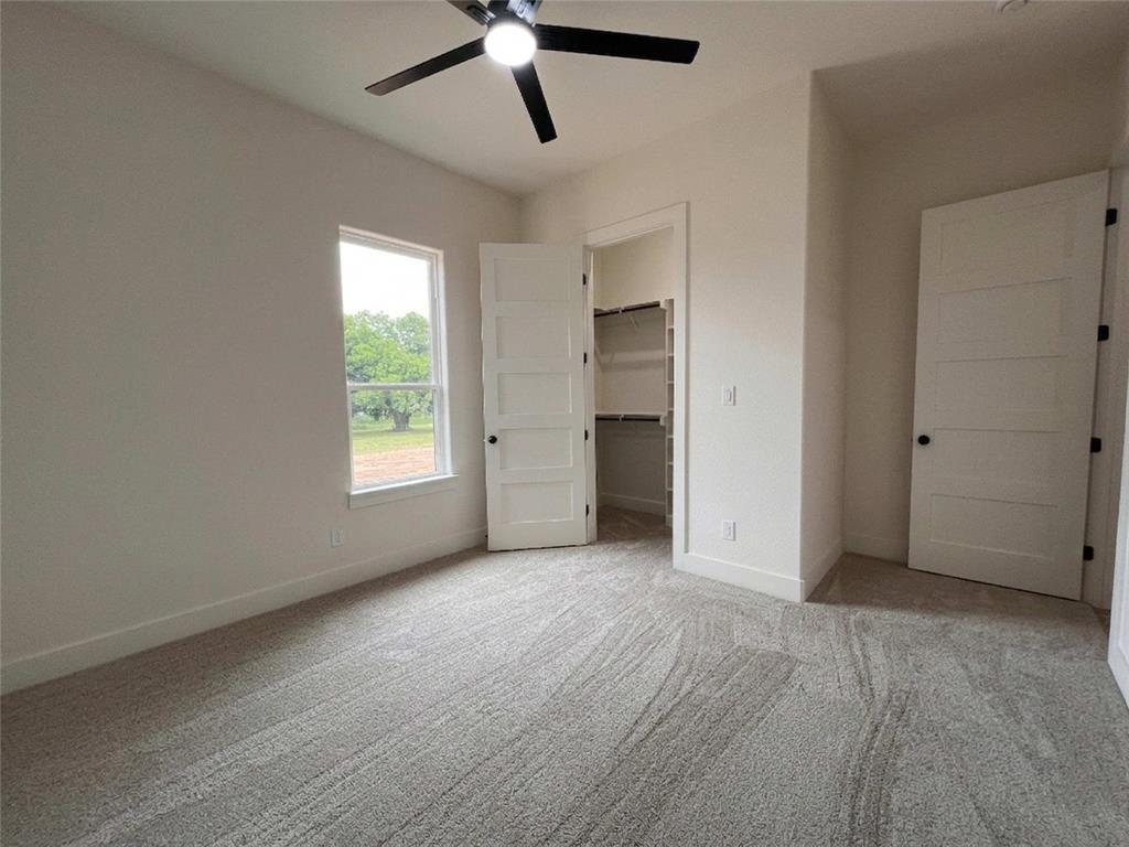 121 Cartwright Park Road Weatherford, TX 76087 - Photo 13 of 17 Carpeted room with a modern ceiling fan, a window, and a built-in closet with shelving