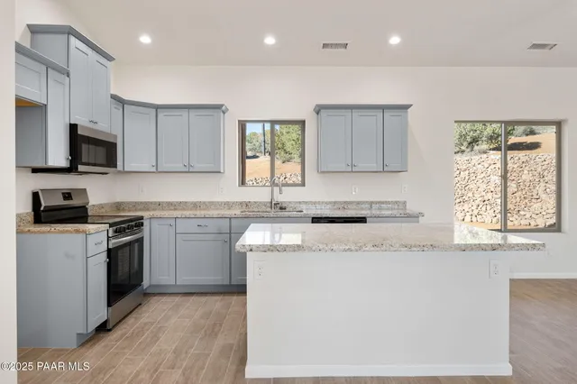 a kitchen with stainless steel appliances granite countertop a stove a sink and a microwave