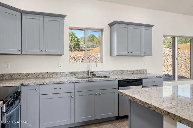 a kitchen with granite countertop stainless steel appliances white cabinets granite counter tops and a window