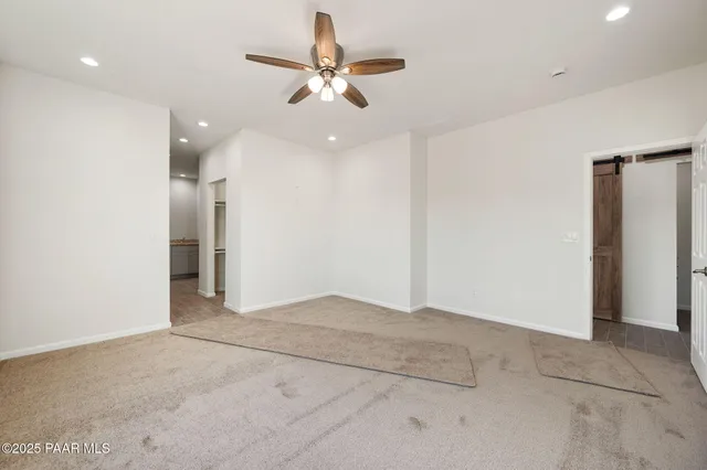 an empty room with closet and a ceiling fan