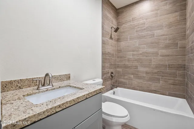 a bathroom with a granite countertop bathtub sink vanity mirror and toilet