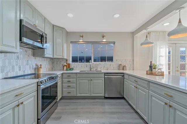 a kitchen with stainless steel appliances granite countertop a stove top oven a sink dishwasher and white cabinets with wooden floor