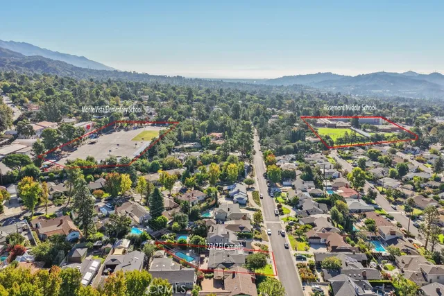 an aerial view of residential houses with outdoor space and trees