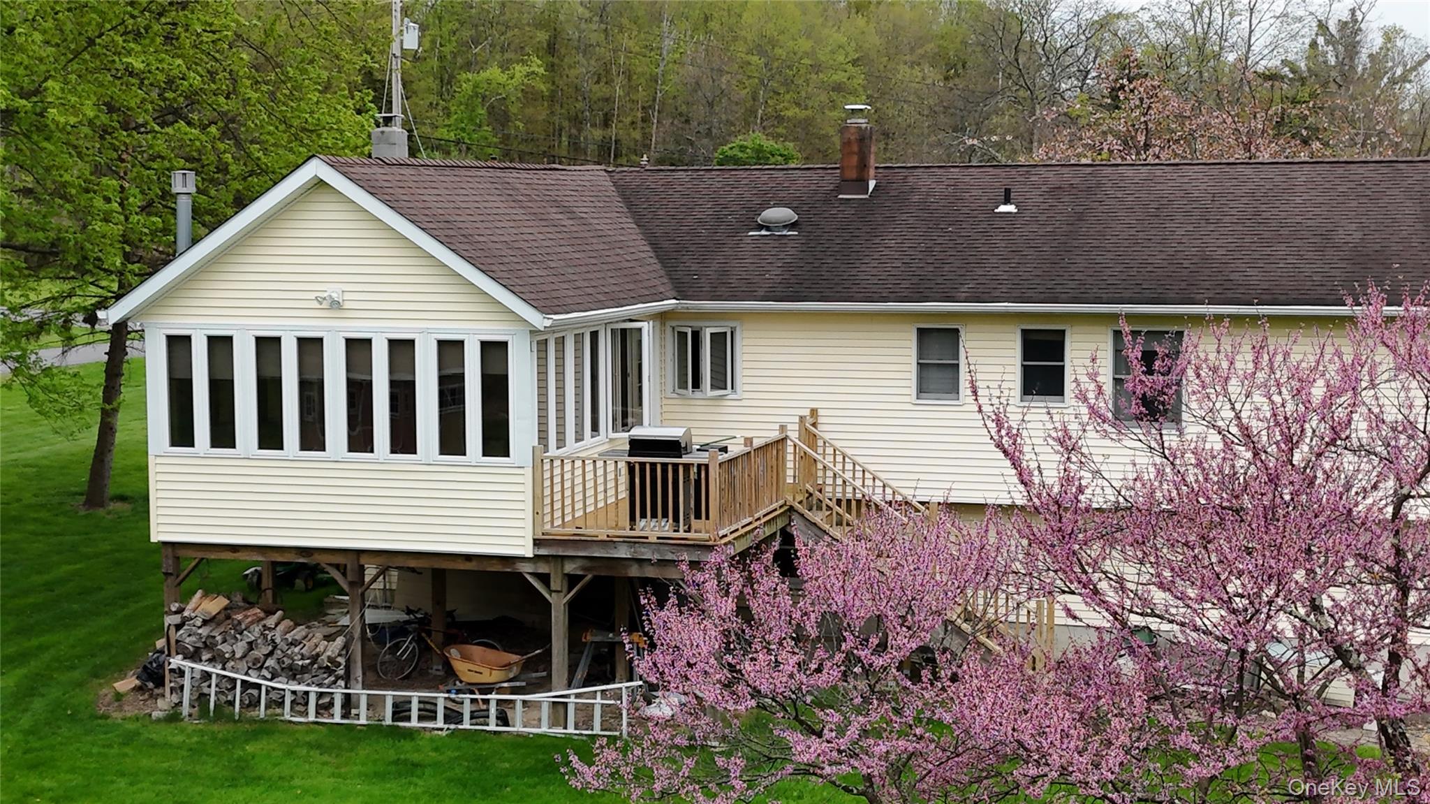 94 Booth Road Chester, NY 10918 - Photo 20 of 21 Rear exterior featuring a sunroom over storage space, an elevated wood deck with stairs, and flowering trees