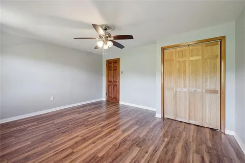 an empty room with wooden floor closet and fan