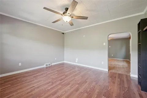 an empty room with wooden floor and fan
