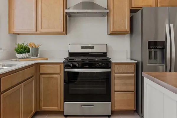 a kitchen with stainless steel appliances white cabinets and a stove a refrigerator with wooden floor
