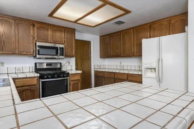 a kitchen with stainless steel appliances granite countertop a stove a sink and a refrigerator