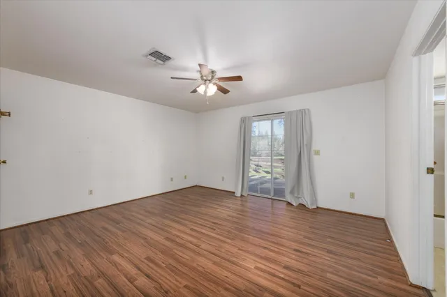 a view of an empty room with a window and wooden floor