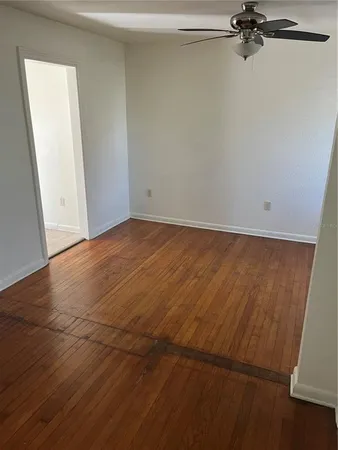 a view of a room with wooden floor and a ceiling fan