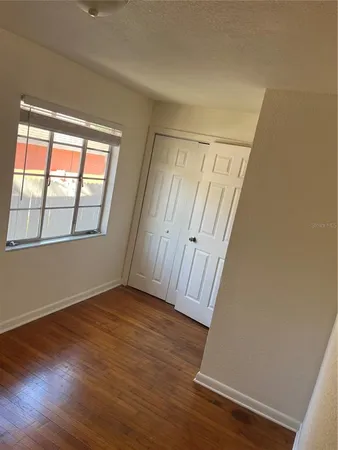 a view of an empty room with wooden floor and a window