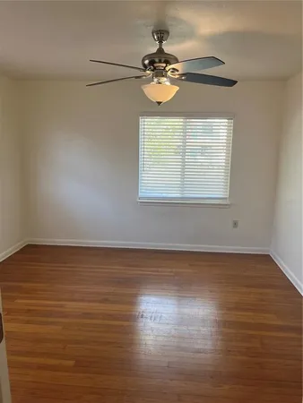 an empty room with wooden floor fan and windows
