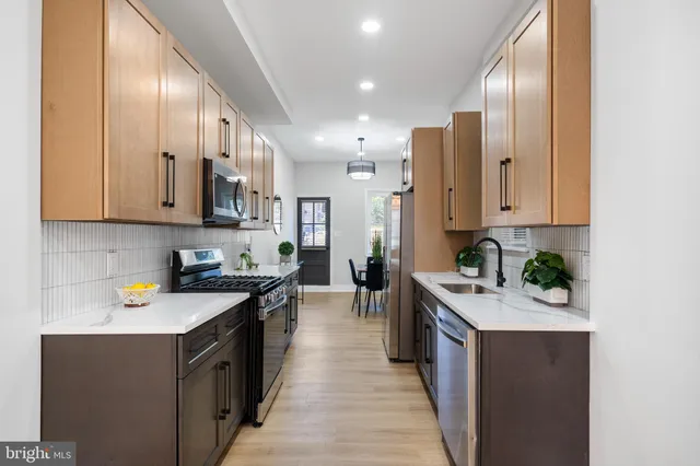 a kitchen with stainless steel appliances a stove a sink cabinets and a wooden floor