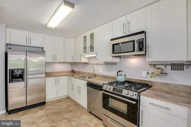 a kitchen with stainless steel appliances granite countertop white cabinets a stove a microwave and a refrigerator