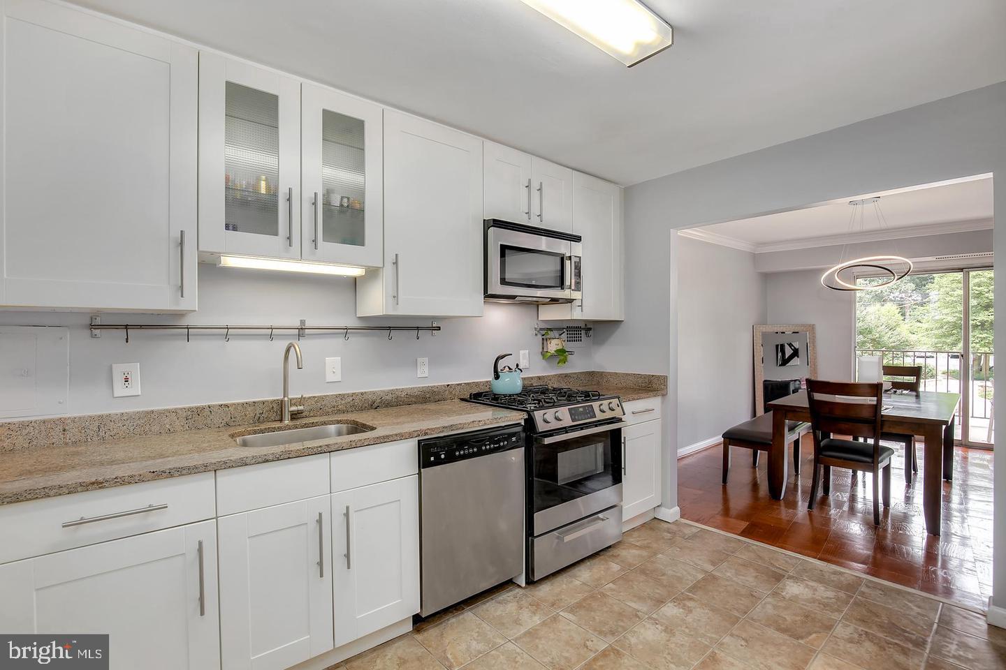 9039 Sligo Creek Parkway, Unit 205 Silver Spring, MD 20901 - Photo 9 of 28 a kitchen with granite countertop a stove top oven sink and cabinets