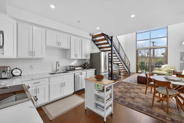 a living room with furniture a large window and kitchen view