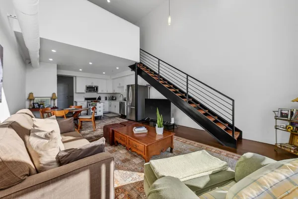 a living room with furniture kitchen view and a wooden floor